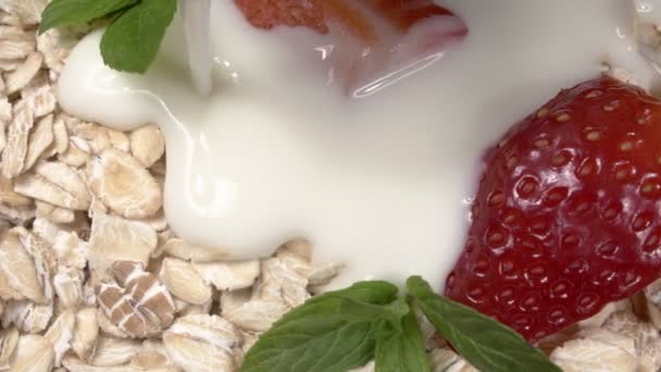 Muesli met verse aardbeien en munt met close-up yoghurt. — Stockvideo