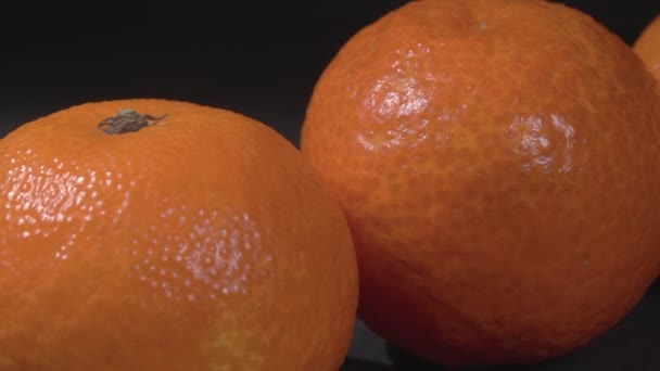 Les tangerines se rapprochent sur un fond noir. La rotation des fruits tropicaux. — Video
