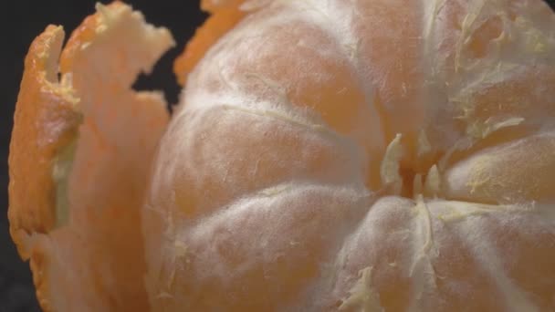 Citrus close-up. Mandarin with peeled skin. Black background. — Stock Video