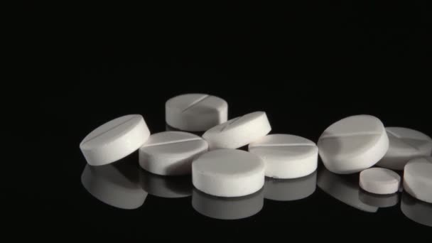 Pílulas brancas em um fundo preto close-up. — Vídeo de Stock