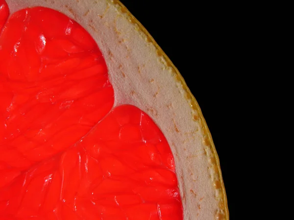 A fragment of grapefruit close-up on a black background. Organic fruit. Stock Picture
