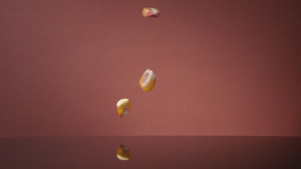 Granos de maíz voladores sobre un fondo de color. Super cámara lenta. — Vídeos de Stock
