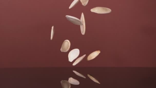 Létající dýňová semínka na hnědém pozadí. Super zpomalený. — Stock video
