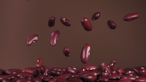 Vliegende rode bonen op een bruine achtergrond. Super slow motion. — Stockvideo