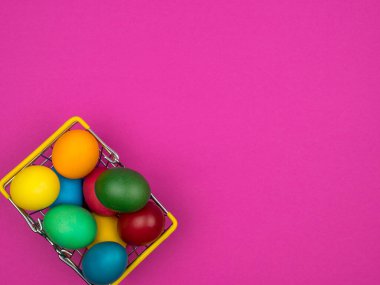Easter eggs in a metal basket. Bright pink background.