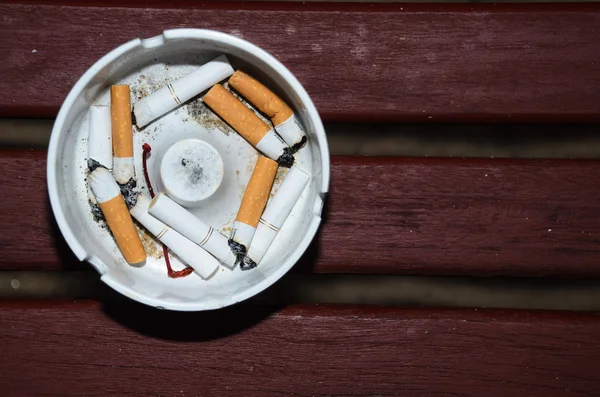 Cigarettes fumées en cendrier blanc sur table en bois — Photo