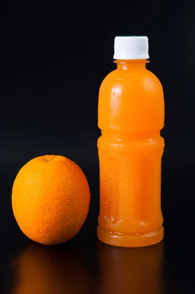 Zumo de naranja en una botella y naranja a su lado aislado en negro —  Fotos de Stock