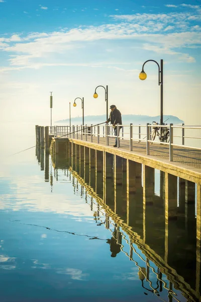 トラジメーノ湖と年配の男性の釣り桟橋 ストック画像