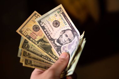 Close up of man holding in his hand notes varying values of United States dollars
