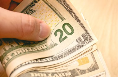 Close up of man holding in his hand notes varying values of United States dollars