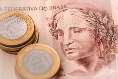 Close-up view of Brazilian Real banknotes and coins on a wooden table
