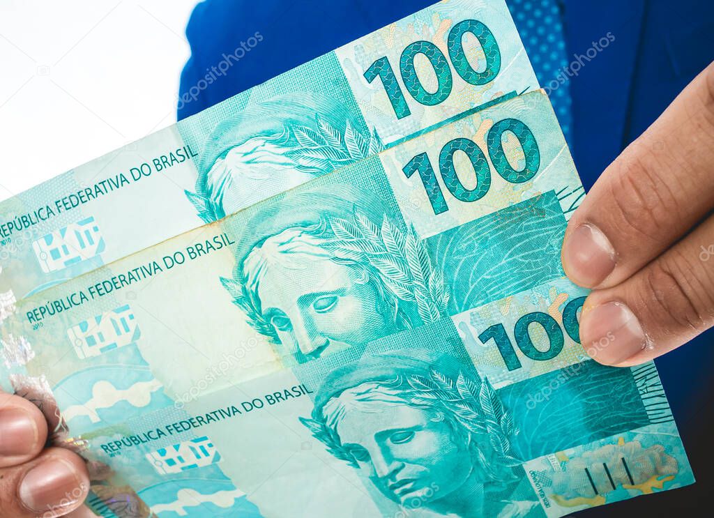 Real currency, money from Brazil. Brasil, Dinheiro, Reais, Hand. People holding in hand a brazilian banknotes.