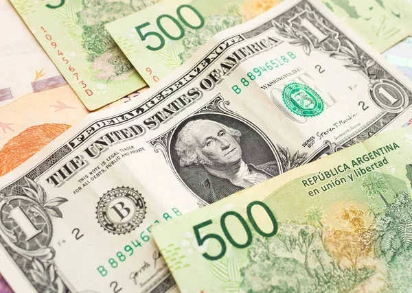 Argentinian peso. Money notes of the argetina's currency and a US dollar bill to represent the foreign exchange theme.
