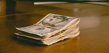 Folded US dollar bills on a wooden desk. Finance, Business, save money and Economy concepts.
