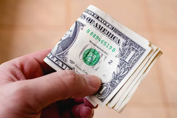 Man holding 1 us dollar bills in hand. Finance and economics concepts.