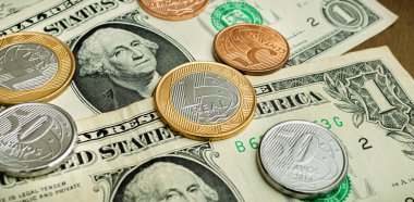 Brazilian coins and a US One Dollar bills on a wooden table. Top View photo. Foreign exchange market concept.