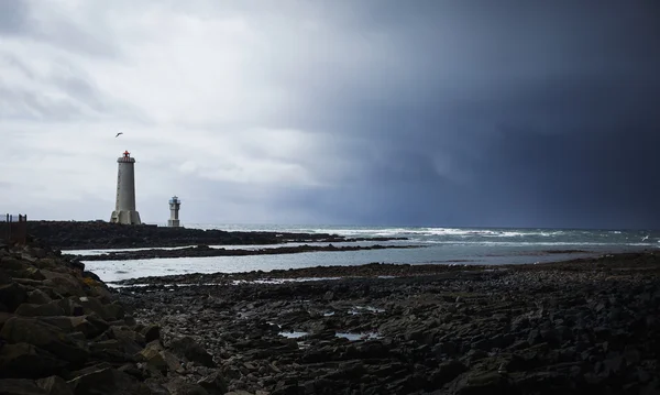 Farol, quebrando ondas e depois do sol atrás de uma nuvem escura — Fotografia de Stock