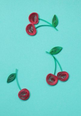 Güzel olgun kirazlar mavi arka planda izole edilmiş. Kağıt quilling kiraz - taze meyve, doğal meyve. Köklü ve yeşil yapraklı meyveler. El yapımı kağıt tüy dökme tekniği.