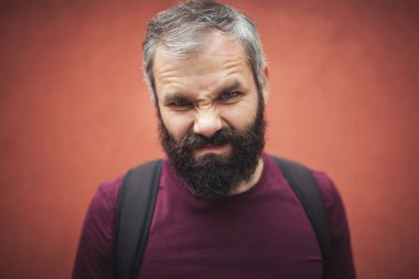 Kameraya bakan komik bir adamın portresi. kızgın yüz ifadesi. Genç ve vahşi. Erkek berber bakımı. Sakallı, olgun bir hippi. Bıyıklı, vahşi, beyaz bir hippi. Saç ve sakal bakımı. Ciddi yüz..