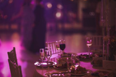 Elegant celebration with vibrant lights and sparkling drinks at a beautifully set table in a lively event space during an evening gathering