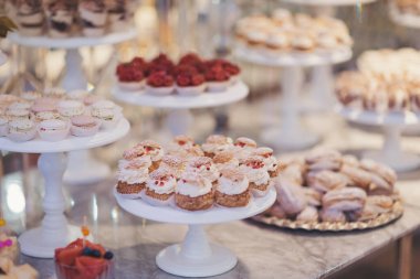 Canlı bir pastanede zarif tezgahlarda sergilenen enfes tatlılar. Çok çeşitli güzel hazırlanmış hamur işleri beyaz stantların üzerinde oturur, kremalı süslemeler, meyve süsleri ve kurabiyeler sergilenir. 