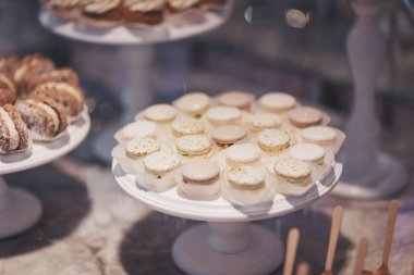 Canlı bir pastanede zarif tezgahlarda sergilenen enfes tatlılar. Çok çeşitli güzel hazırlanmış hamur işleri beyaz stantların üzerinde oturur, kremalı süslemeler, meyve süsleri ve kurabiyeler sergilenir. 