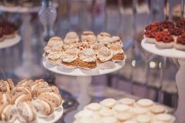 Canlı bir pastanede zarif tezgahlarda sergilenen enfes tatlılar. Çok çeşitli güzel hazırlanmış hamur işleri beyaz stantların üzerinde oturur, kremalı süslemeler, meyve süsleri ve kurabiyeler sergilenir. 