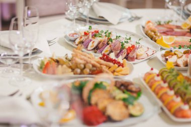 Sıcak ve davetkar bir atmosferde, şenlikli bir toplantı sırasında lezzetli gurme yemekleri güzel bir sofraya serpiştirilir.