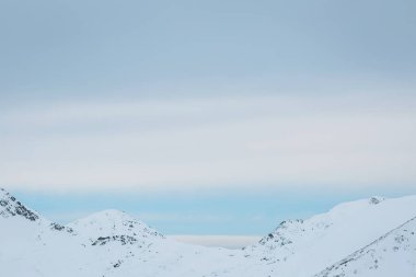 Karla kaplı görkemli zirveler sakin bir kış manzarasında kasvetli bir gökyüzünün altında yükseliyor. Doğanın güzelliğinde keşif ve maceraya davetiye çıkarıyor.