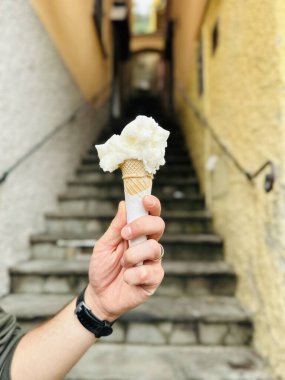 İtalyan şehrinde sanatsal dondurma külahlı tatlı. Turistin elinde waffle külahında İtalyan dondurmasının yakın çekimi. Eski şehrin en iyi dondurması..