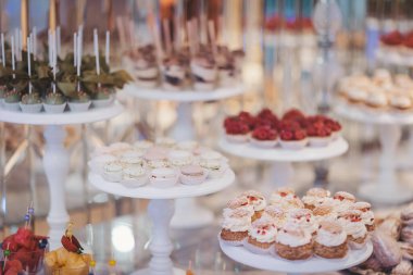 Kapkekler, pastalar ve tatlılar içeren nefis bir tatlı gösterisi. Parlak, zarif bir ortamda, güzel dekorasyonlarla.