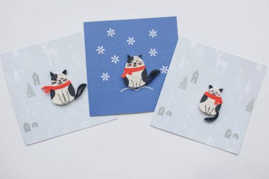 Kırmızı eşarplı ve düşen kar taneli sevimli kedilerin olduğu iskambil kağıtları. Tebrik kartları hazırlıyorum. El yapımı kağıt tüy dökme tekniği. Evde el işi. Hobi, ev ofisi..