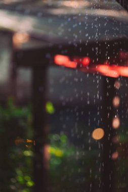 Sıcak bir akşamda yağmur damlaları yumuşak ışıklarla aydınlatılan rahat bir ortamda hafifçe düşüyor.