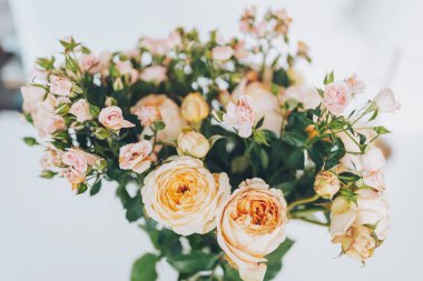 Yumuşak renklerde taze güller bir masanın üzerine güzelce dizilmiş, odayı doğal zarafetle aydınlatıyor.