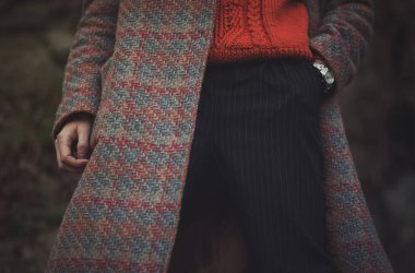 Rahat turuncu bir süveter, desenli bir ceket ve serin sezonda kentsel bir ortamda giyilen şık çizgili pantolona sahip şık bir kış kıyafeti.