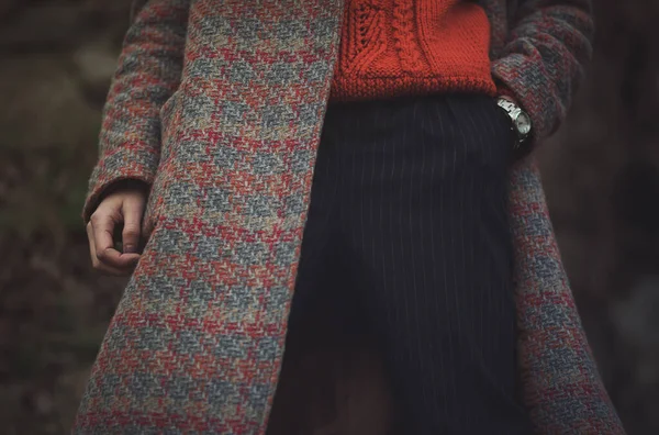 Rahat turuncu bir süveter, desenli bir ceket ve serin sezonda kentsel bir ortamda giyilen şık çizgili pantolona sahip şık bir kış kıyafeti.