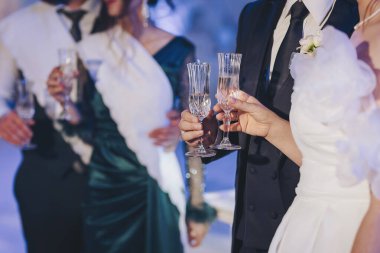 Bir kutlama etkinliğinde ellerinde bardaklar olan bir grup insan resmi bir ortamda aile ve arkadaşlarla bir araya geliyor.