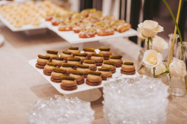 Masalar bir etkinlikte düzenli olarak düzenlenmiş çeşitli atıştırmalık ve ikramlar barındırır. Çiçekler yakındaki vazolara konur. Konuklar sergilenen şekerleri beğenebilir