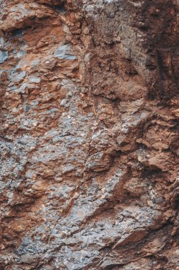 Detaylı görüntü, dağ yamacında kahverengi ve gri tonlarında kaya katmanları gösteriyor. Güneş ışığı, Dünya 'nın doğal yapısını ve bileşimini gösteren dokuları ve formları ortaya çıkarır.