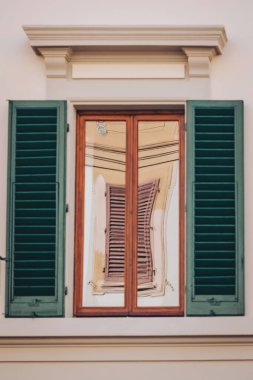 Güneş ışığı yeşil kepenklerin olduğu hoş bir pencereden dans eder, sıcak ve davetkar bir iç mekan ortaya çıkarır. Işık oyunu sahneye biraz sihir katıyor.