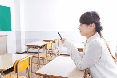 _ a _ mobile _ phone _ in _ class _ in _ kim _. Sınıfta akıllı telefon kullanan öğrenci.