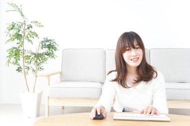 Evde bilgisayar kullanan genç bir kadın.