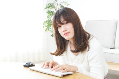 Evde bilgisayar kullanan genç bir kadın.