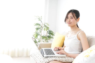 Genç kadın odada dizüstü bilgisayar kullanıyor.