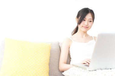 Genç kadın odada dizüstü bilgisayar kullanıyor.