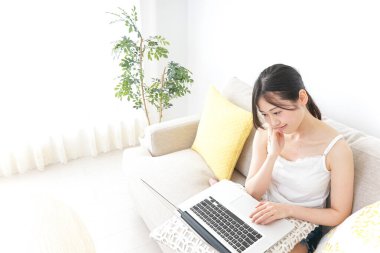 Genç kadın odada dizüstü bilgisayar kullanıyor.