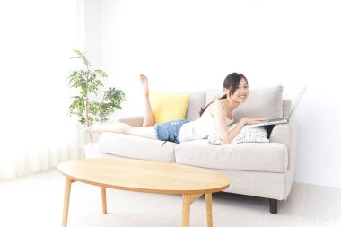 Genç kadın odada dizüstü bilgisayar kullanıyor.