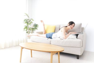 Genç kadın odada dizüstü bilgisayar kullanıyor.