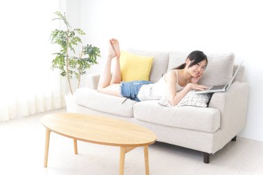 Genç kadın odada dizüstü bilgisayar kullanıyor.