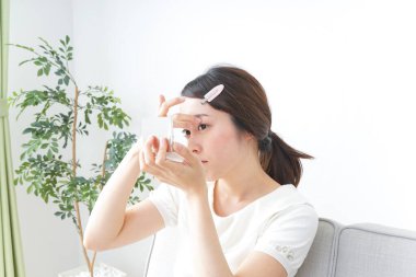 Genç Asyalı kadın makyaj yapıyor.